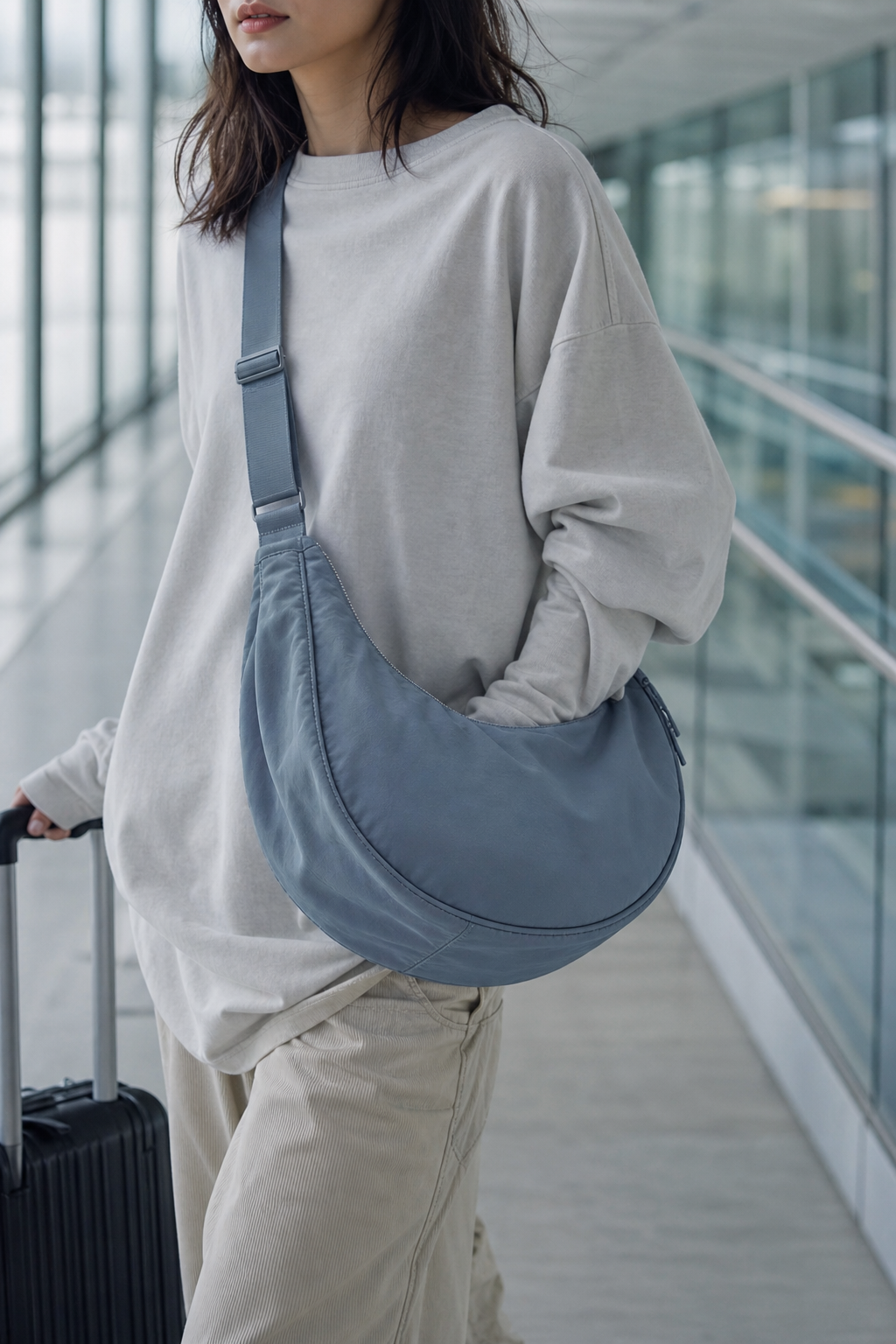 Model wearing blue gray crescent nylon crossbody bag