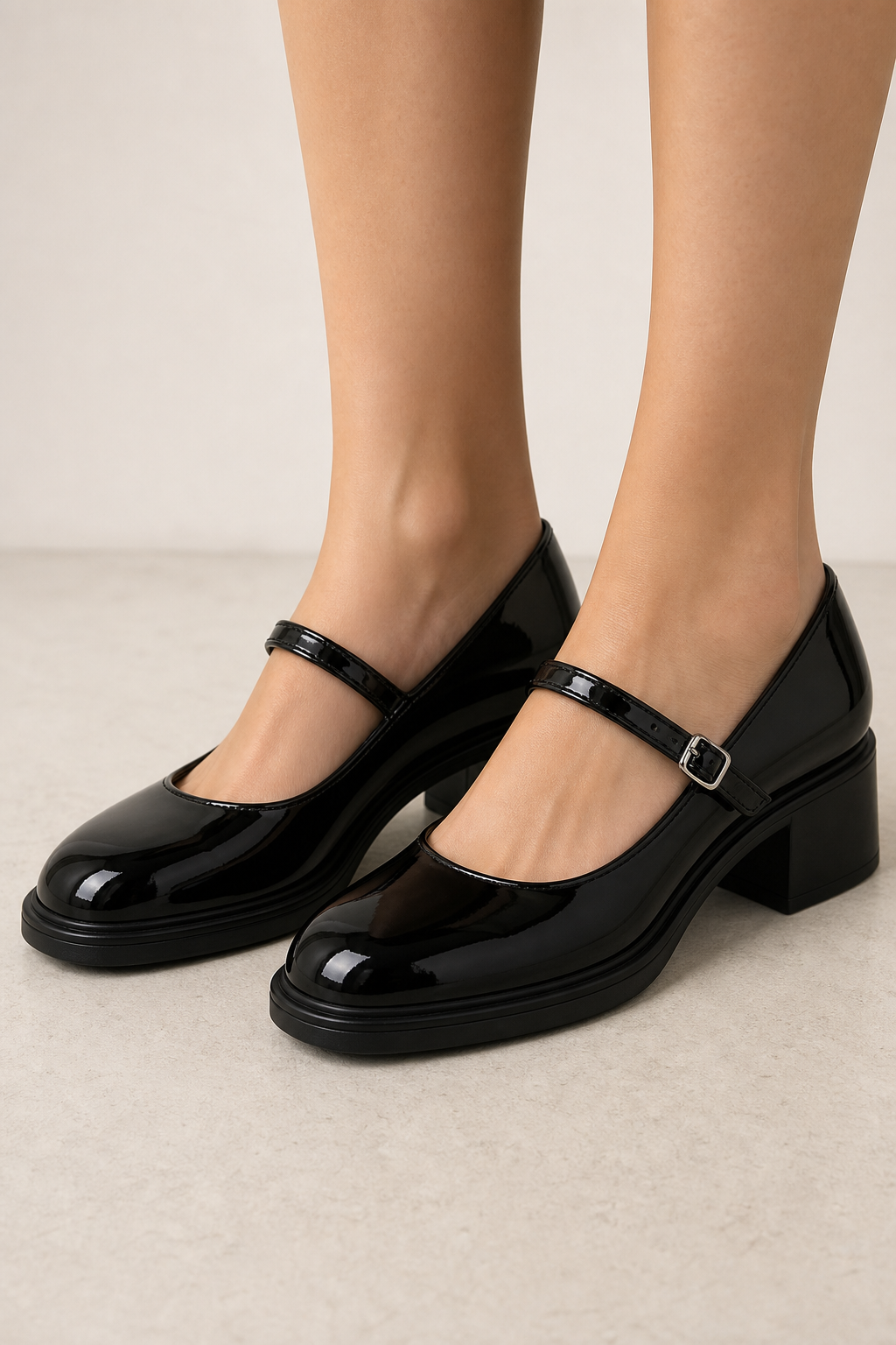 Close-up of black glossy Mary Jane block heel pumps worn on a woman's feet